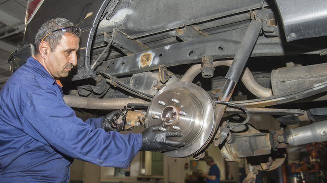 Thalal Khalaf, a new Canadian from Syria, is repairing a car at MacPhee autoshop in Dartmouth Monday