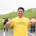 Mohammad Al Masalma smiles for the camera in his yellow shirt at the Walk for Refugees