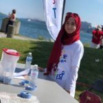 Rayan Shehab standing at a table while volunteering with Nova Multifest