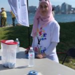 Razan Dervis standing at a table while volunteering at Nova Multifest. 